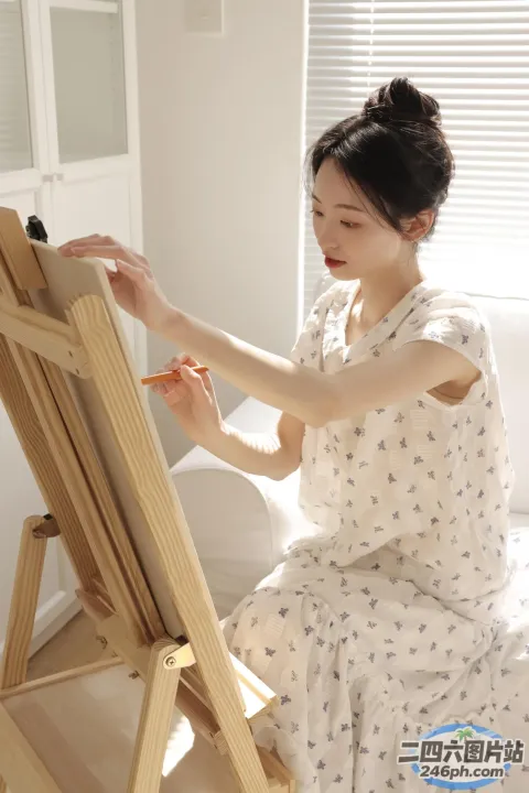 坐在床上的女人在房间的画架上画画