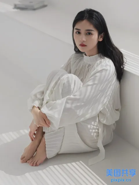 一个穿着白衬衫和裤子的女人坐在地板上
