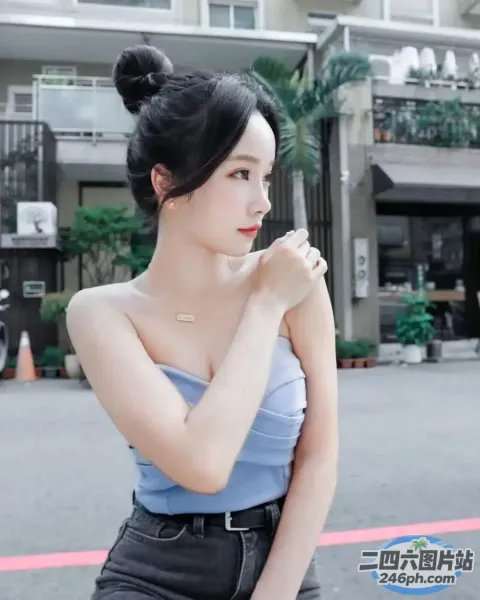 一名身穿蓝色上衣和黑色裤子的女子站在一栋建筑前