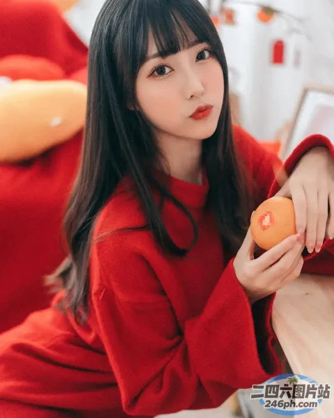 有个女人坐在一张桌子旁，桌上放着一个橘子