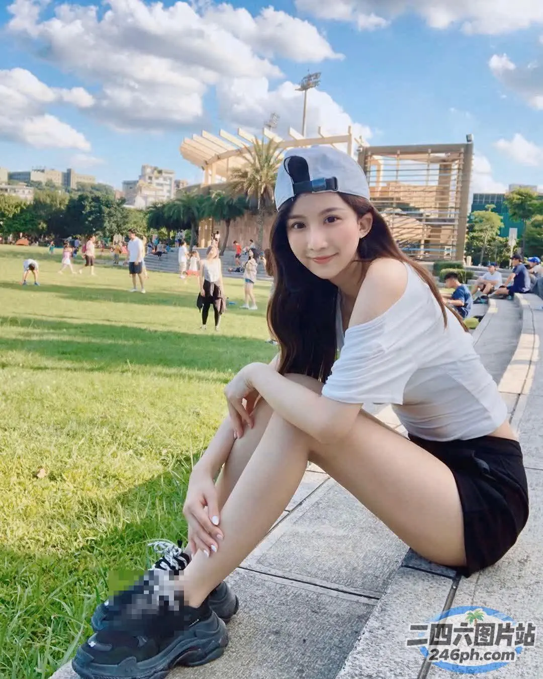一名戴着帽子坐在公园路边的女人