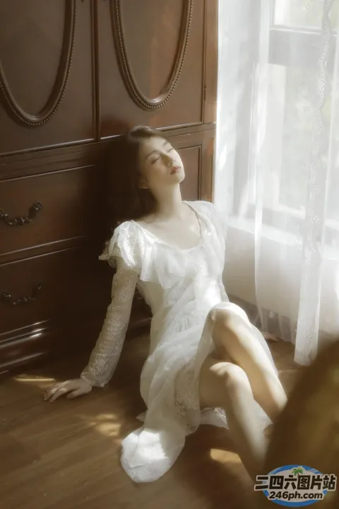 地板上坐着一个穿着白色连衣裙的女人