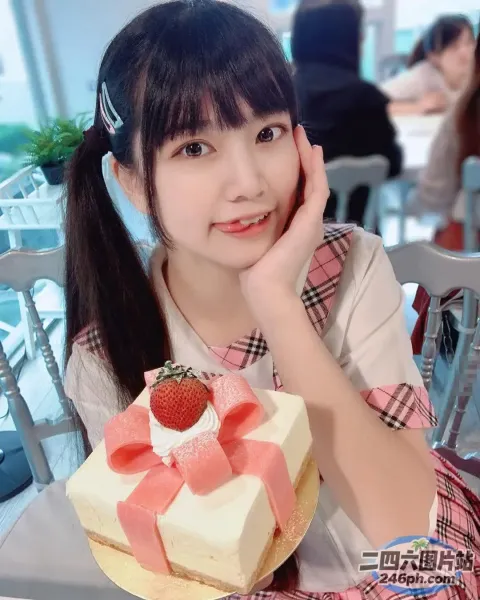 阿拉菲女孩坐在桌子旁，手里拿着蛋糕和草莓