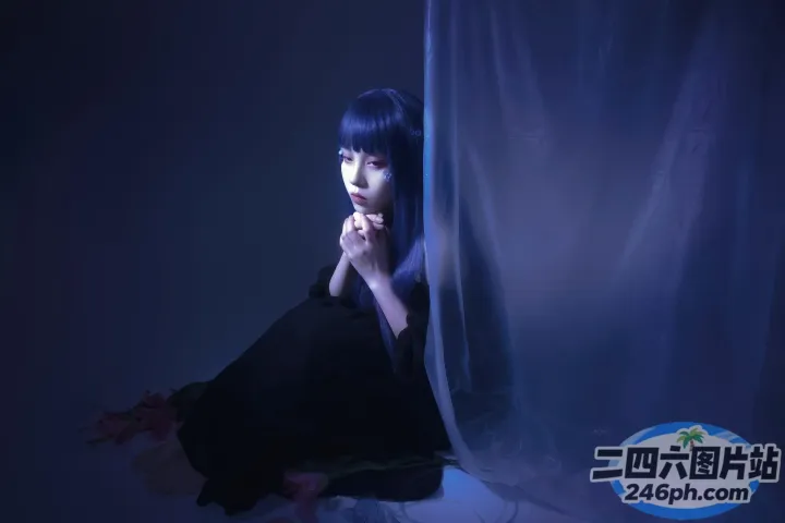 有个女人坐在一张铺着蓝色窗帘的床上