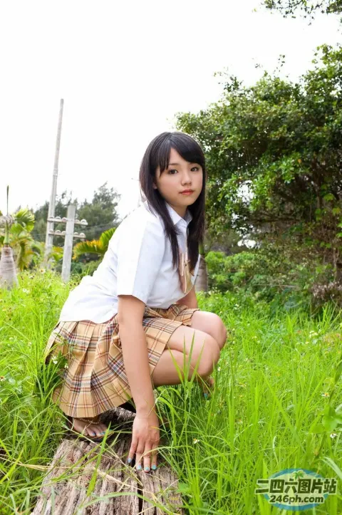 穿着裙子的 arafed 亚洲女孩蹲在田野里