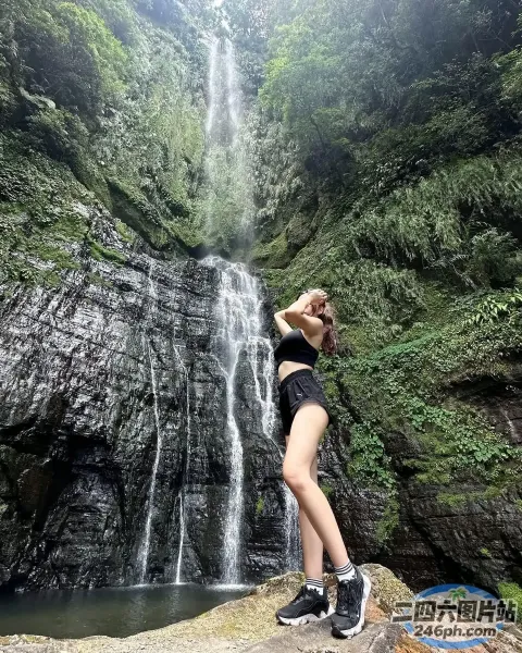 一名身穿黑色比基尼的女子站在瀑布前