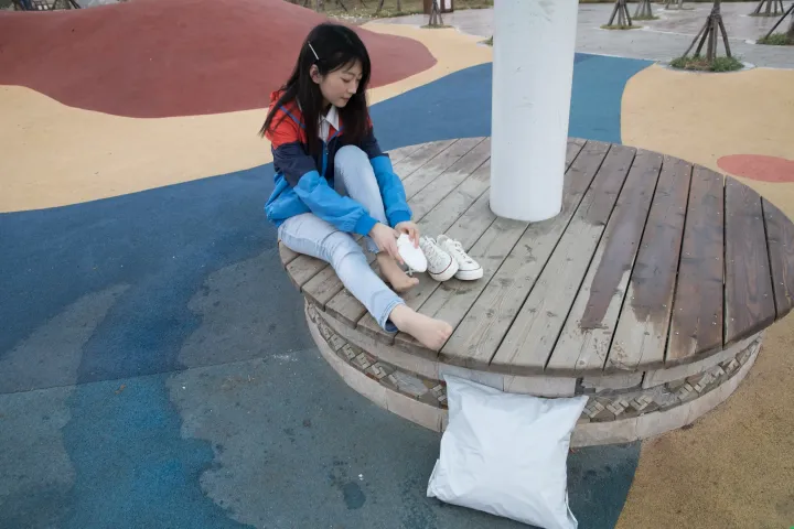 公园的长椅上坐着一个年轻女孩