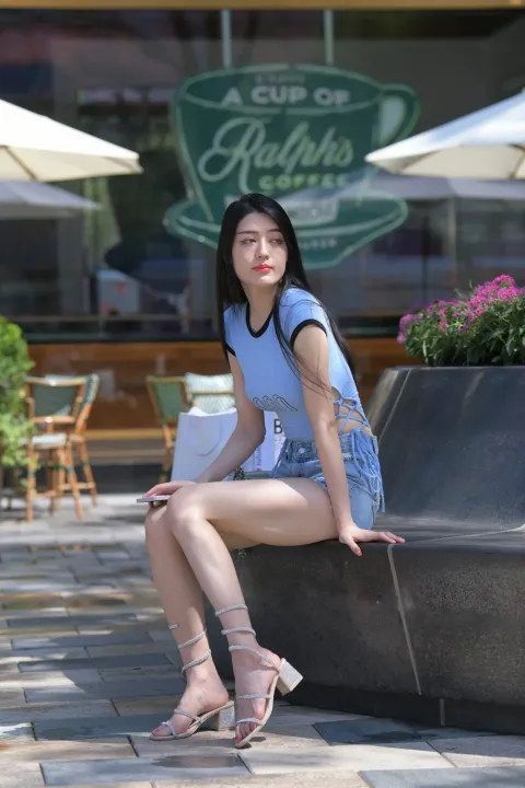 女人拿着包坐在城市的长椅上