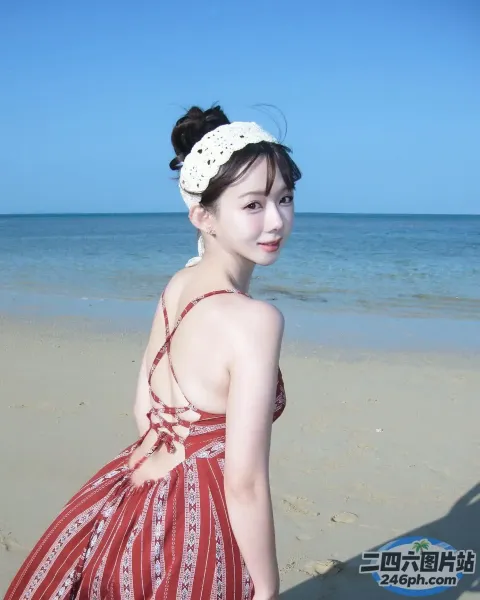 海滩上穿着红色连衣裙的女人，背景是蓝色的海洋