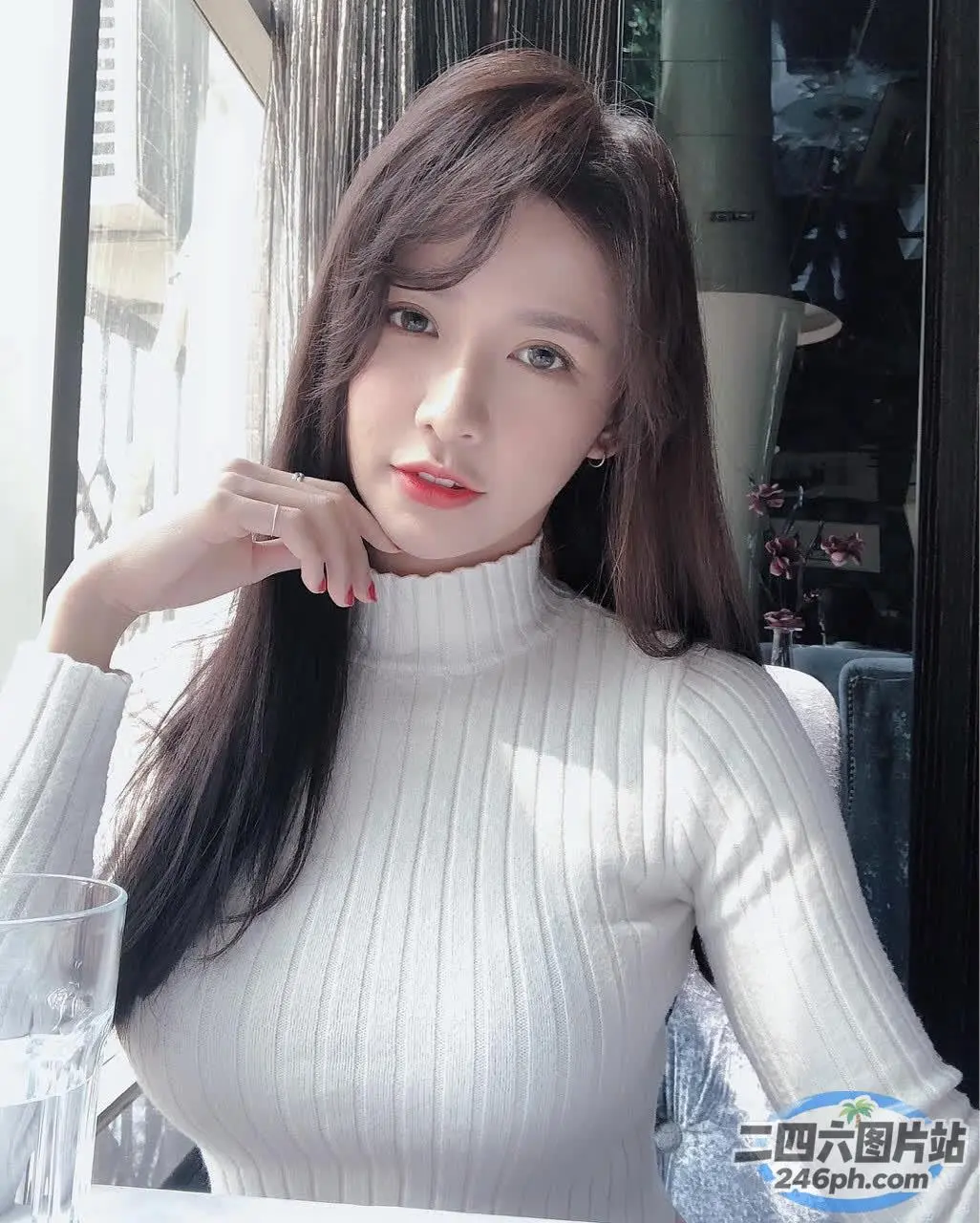 阿拉菲女人坐在桌子旁，手里拿着一杯水