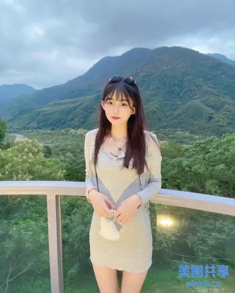 一个女人站在阳台上，背景是一座山