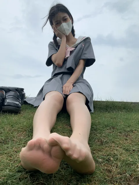 有一个女人坐在草地上，双脚抬起