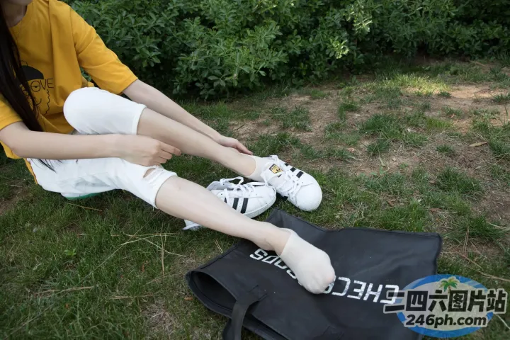 有个女人坐在草地上，脚踩着袋子