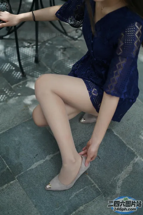 身穿蓝色连衣裙的 Araffe 女子坐在地上系鞋带