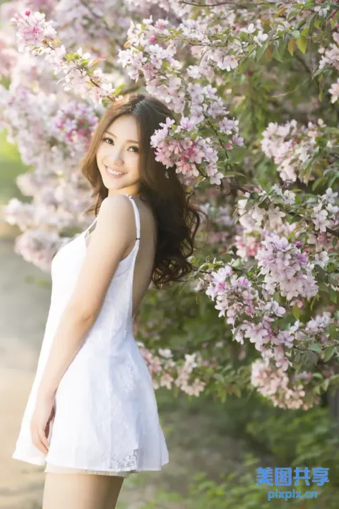 一个穿着白色连衣裙的女人站在树前的特写