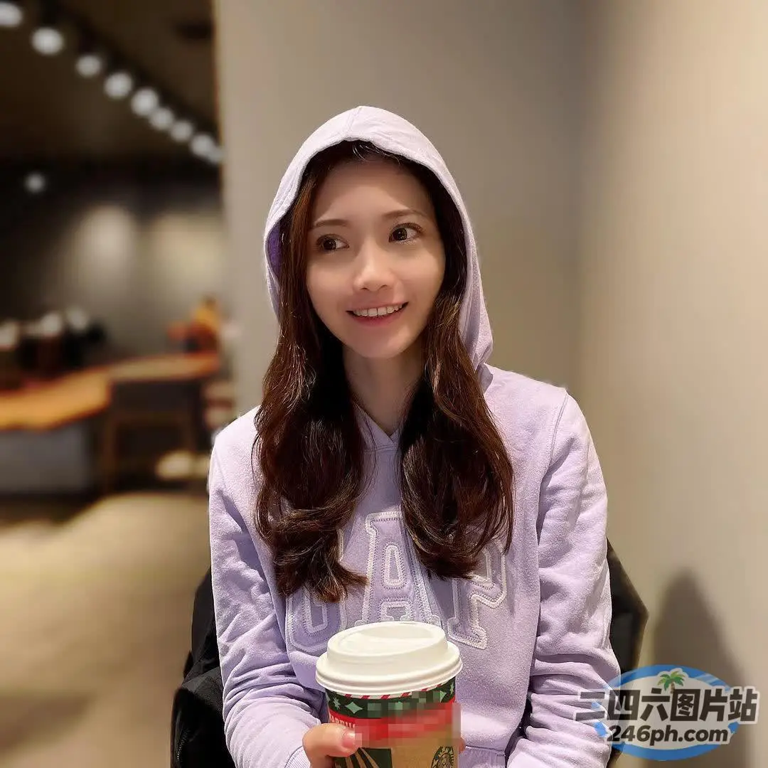 身穿紫色连帽衫的 Araffe 女子手里拿着一杯咖啡