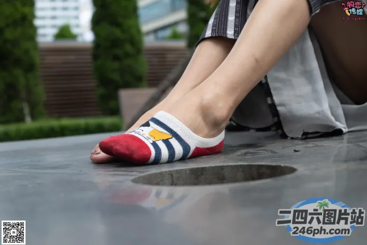有人坐在混凝土表面上，脚踩着一双袜子