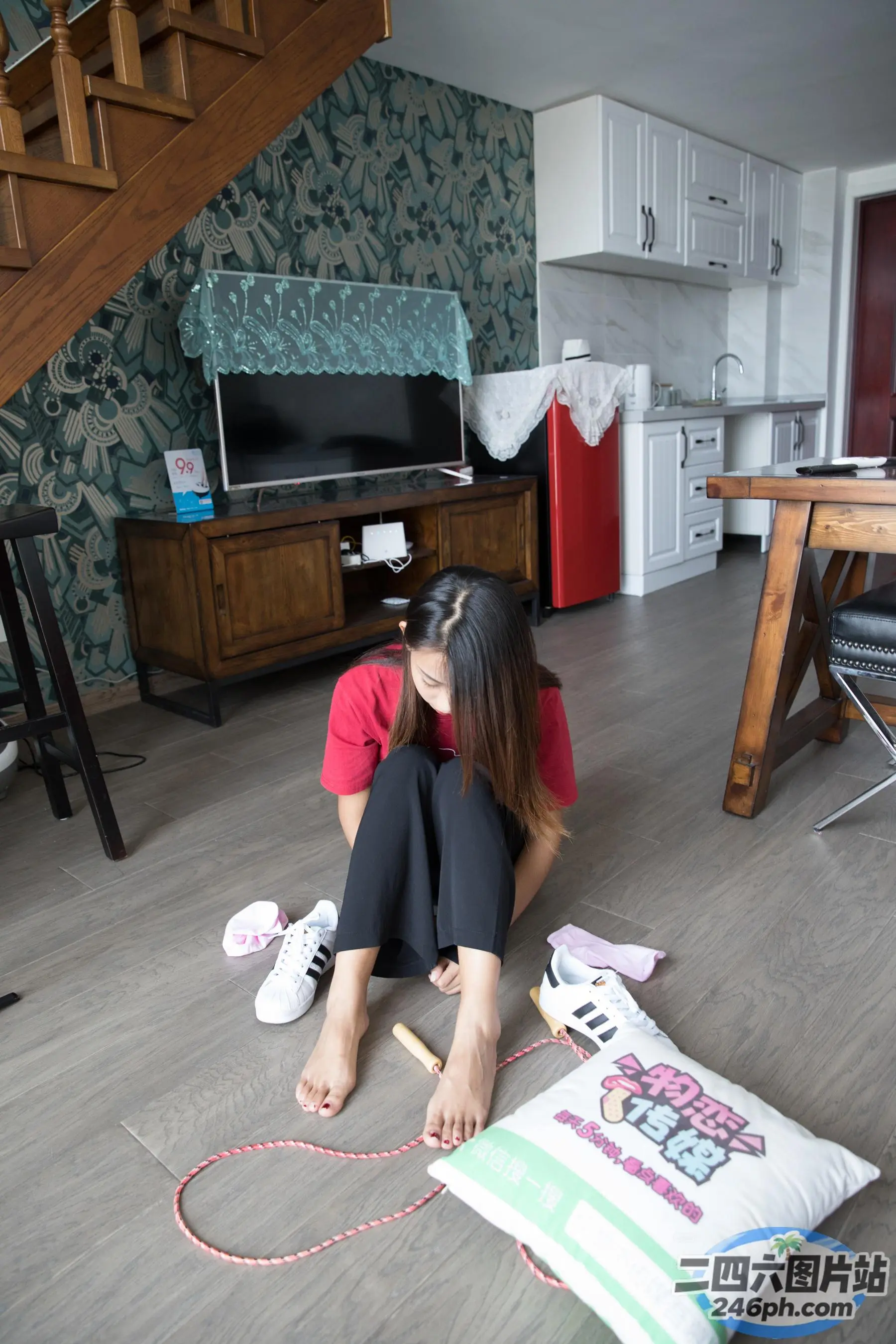 地板上坐着一个女人，手里拿着一个枕头和一个枕头
