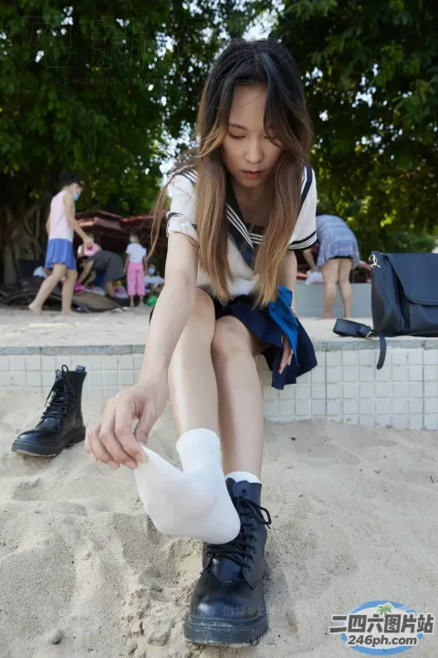 有一个女孩穿着鞋子坐在沙滩上