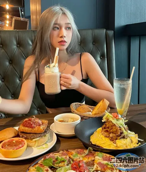 女人坐在一张桌子旁，手里拿着一盘食物和一杯饮料