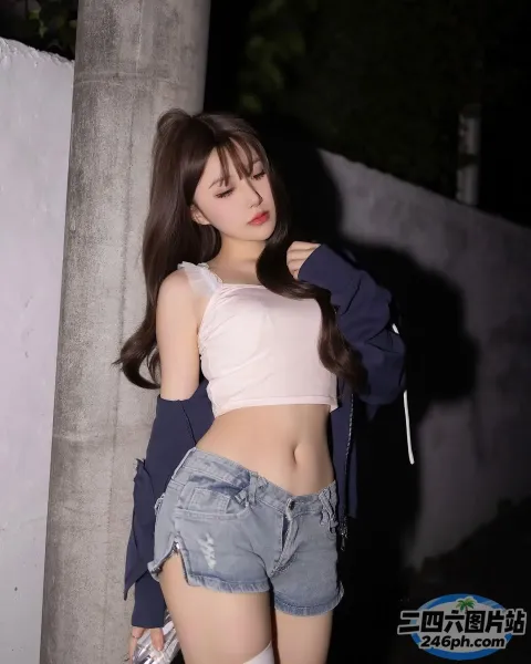 一个穿着短裙和夹克的女人靠在墙上