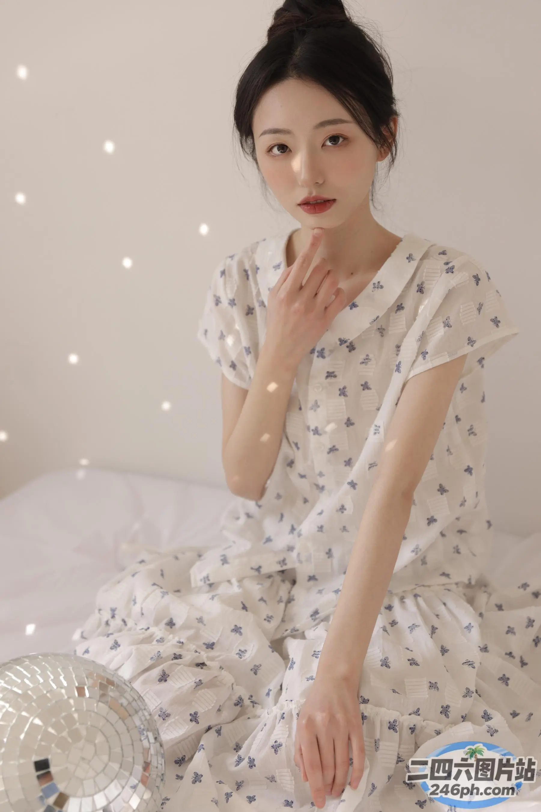 有一个女人坐在床上，床上放着一个镜子球