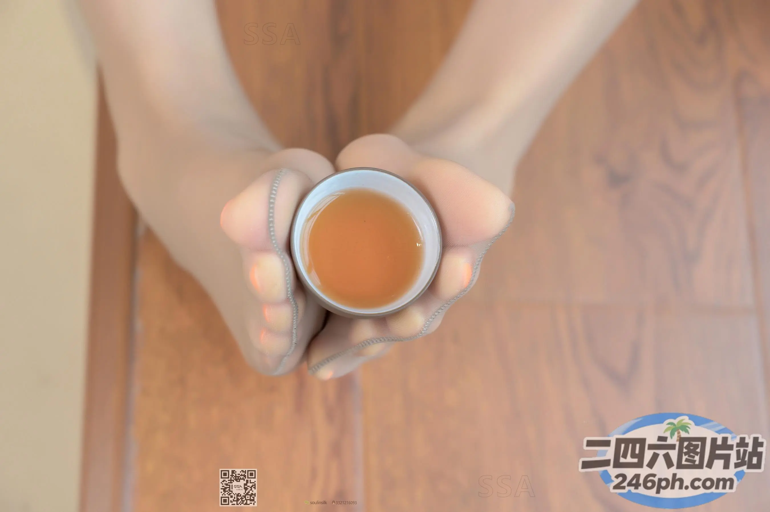有人手里拿着一杯茶，放在木地板上