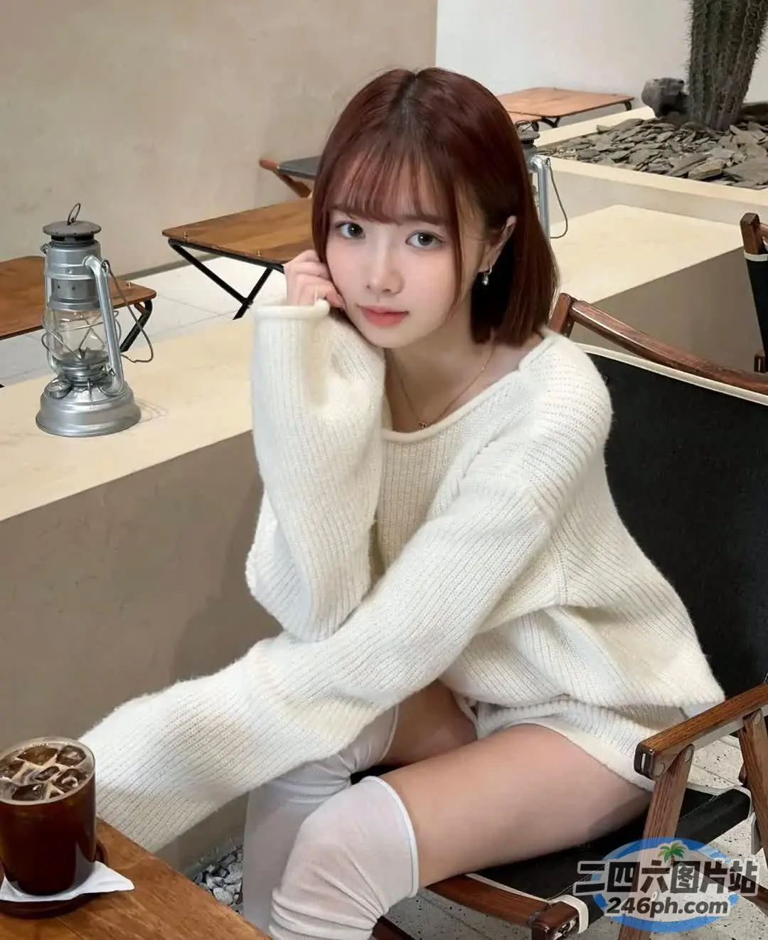 阿拉菲女人坐在桌子旁，手里拿着一杯咖啡