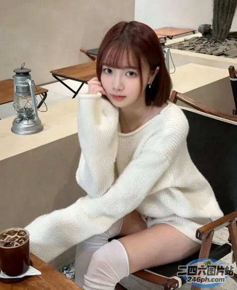 阿拉菲女人坐在桌子旁，手里拿着一杯咖啡