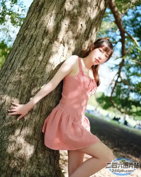 穿着粉红色连衣裙靠在树上的阿拉夫德亚洲女子