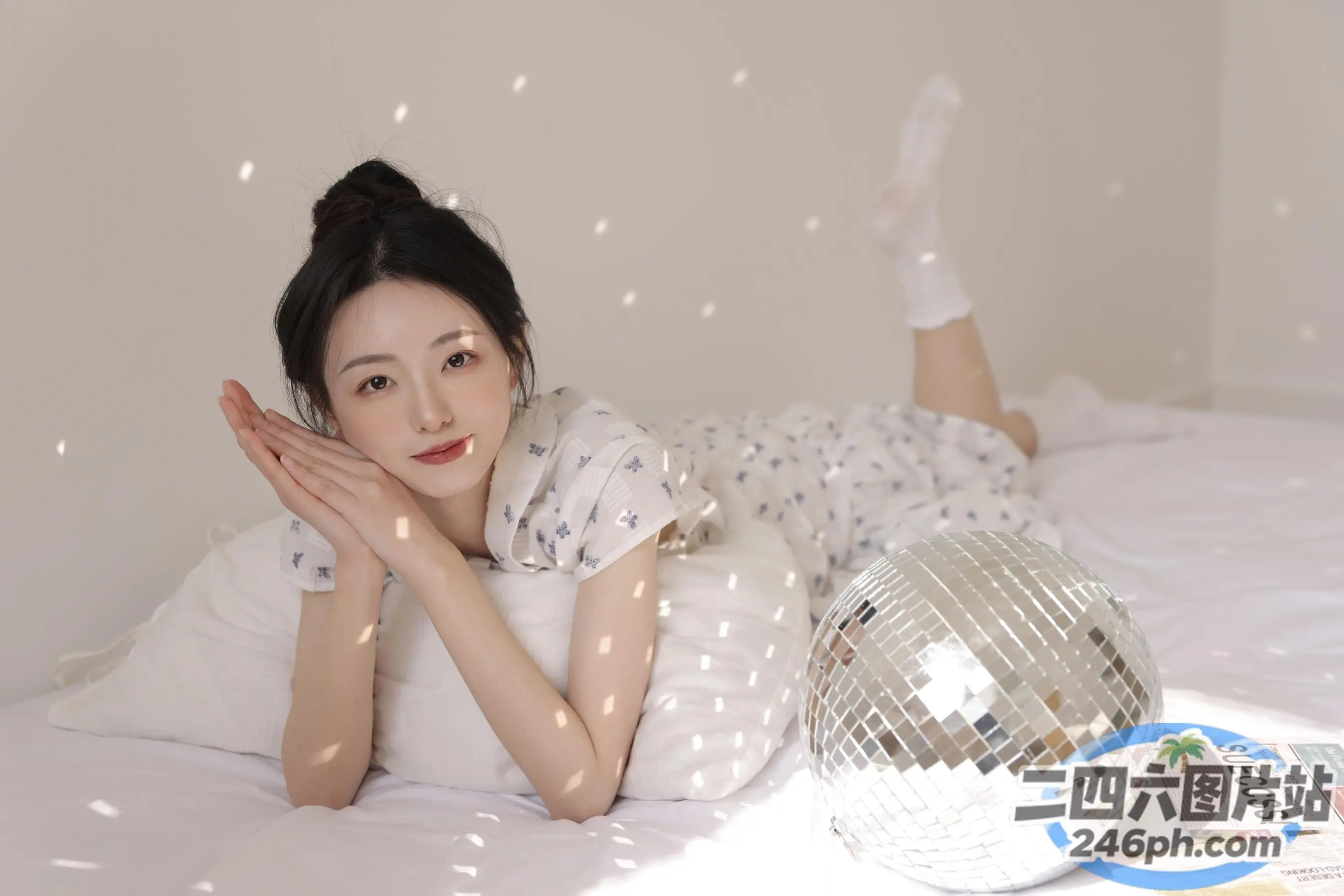有一个女人躺在床上，手里拿着迪斯科球