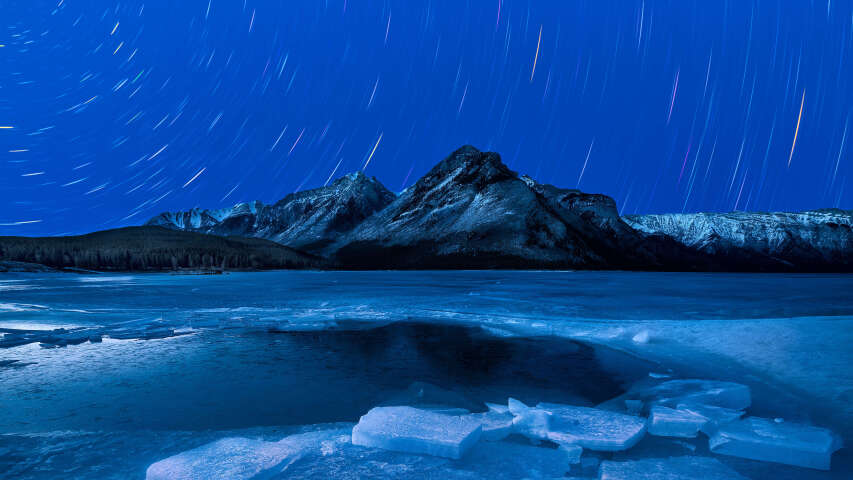 结冰的湖面上的星空，背景是一座山