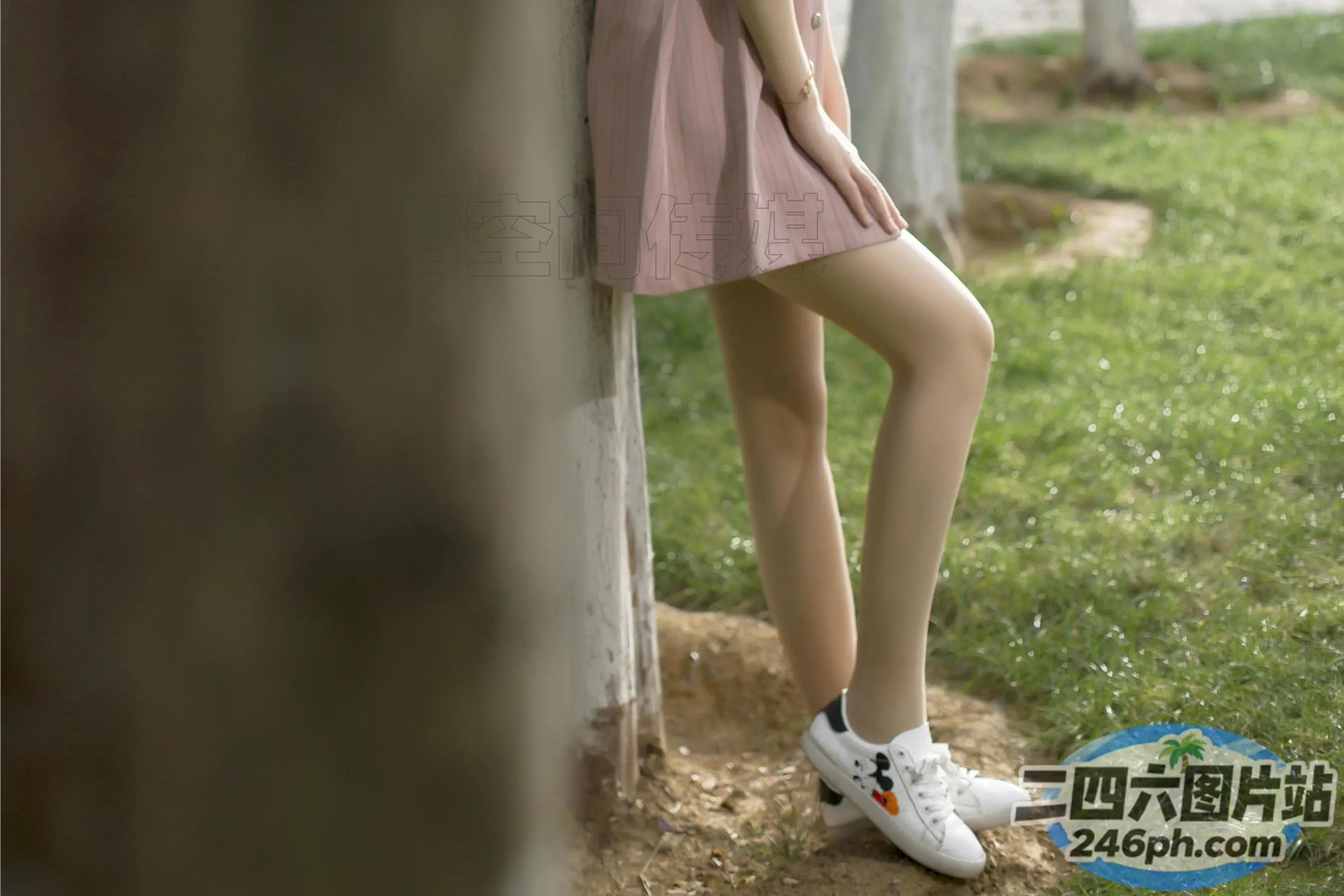有一个女人靠在墙上，双腿交叉