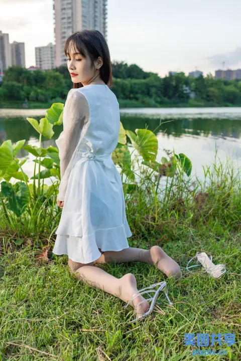 一名妇女坐在水体附近的草地上