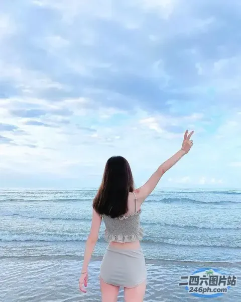 站在海滩上，双臂伸向空中的女人