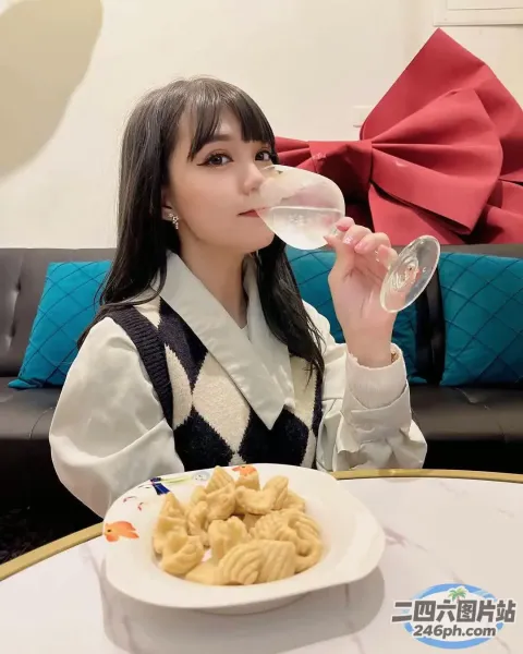 Araffe 女孩坐在桌子旁用玻璃杯喝水