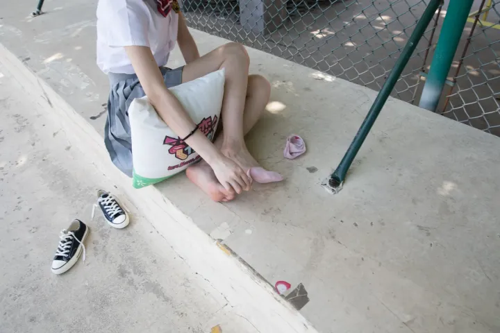 路边坐着一个女人，双脚撑着