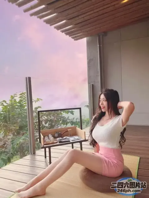 一个女人坐在阳台上的垫子上，可以看到风景
