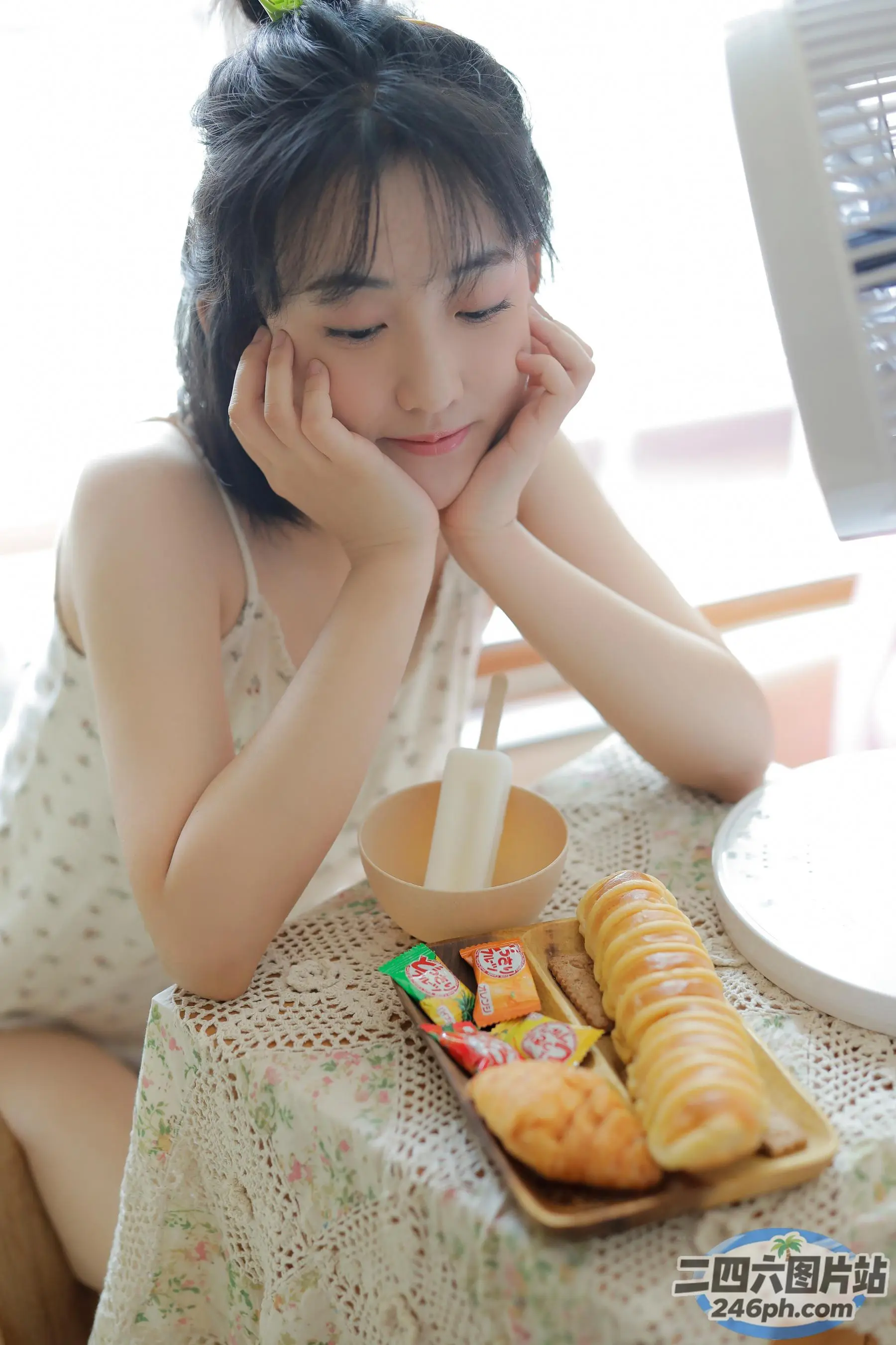 阿拉菲女孩坐在桌子旁，手里拿着一盘食物和一把扇子