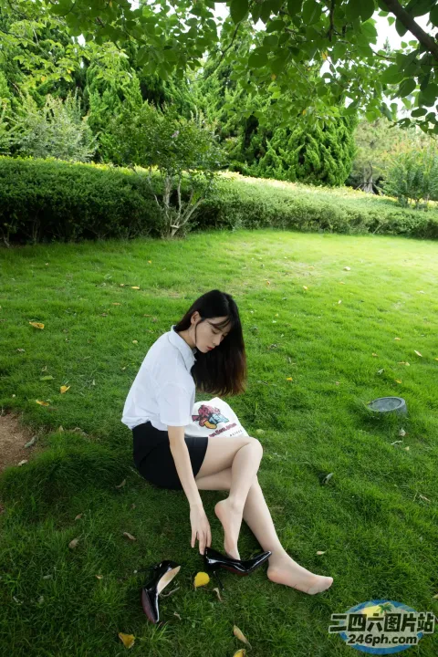 阿拉夫德女人坐在公园的草地上，手里拿着一本书