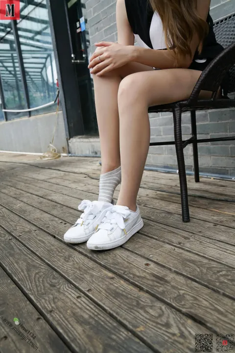 双腿交叉坐在长凳上的阿拉菲德女人