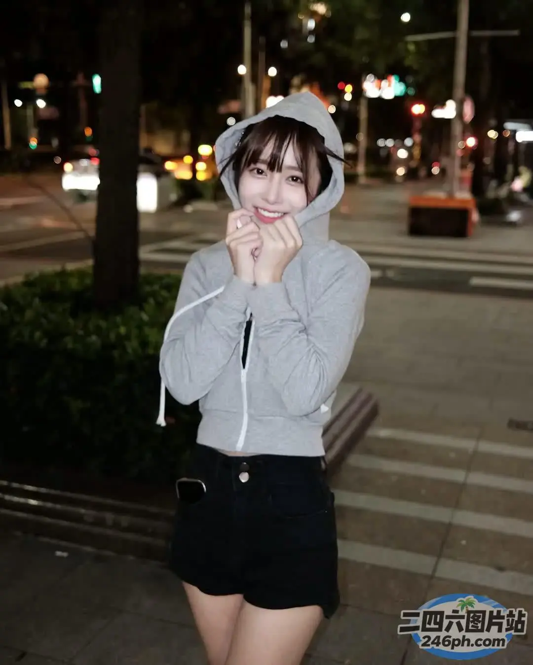 人行道上站着一个穿着连帽衫的女人