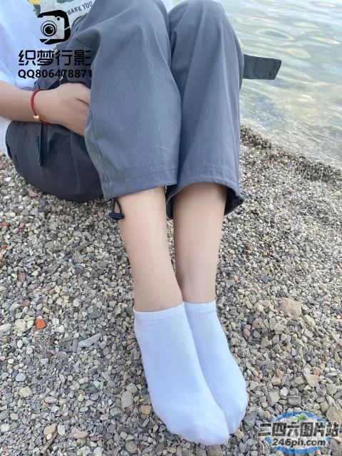 一个人穿着一双袜子坐在海滩上的特写