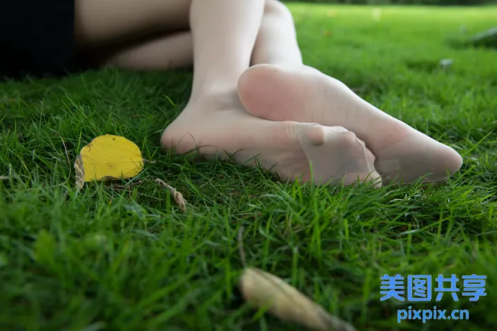 有一个女人坐在草地上，双脚抬起