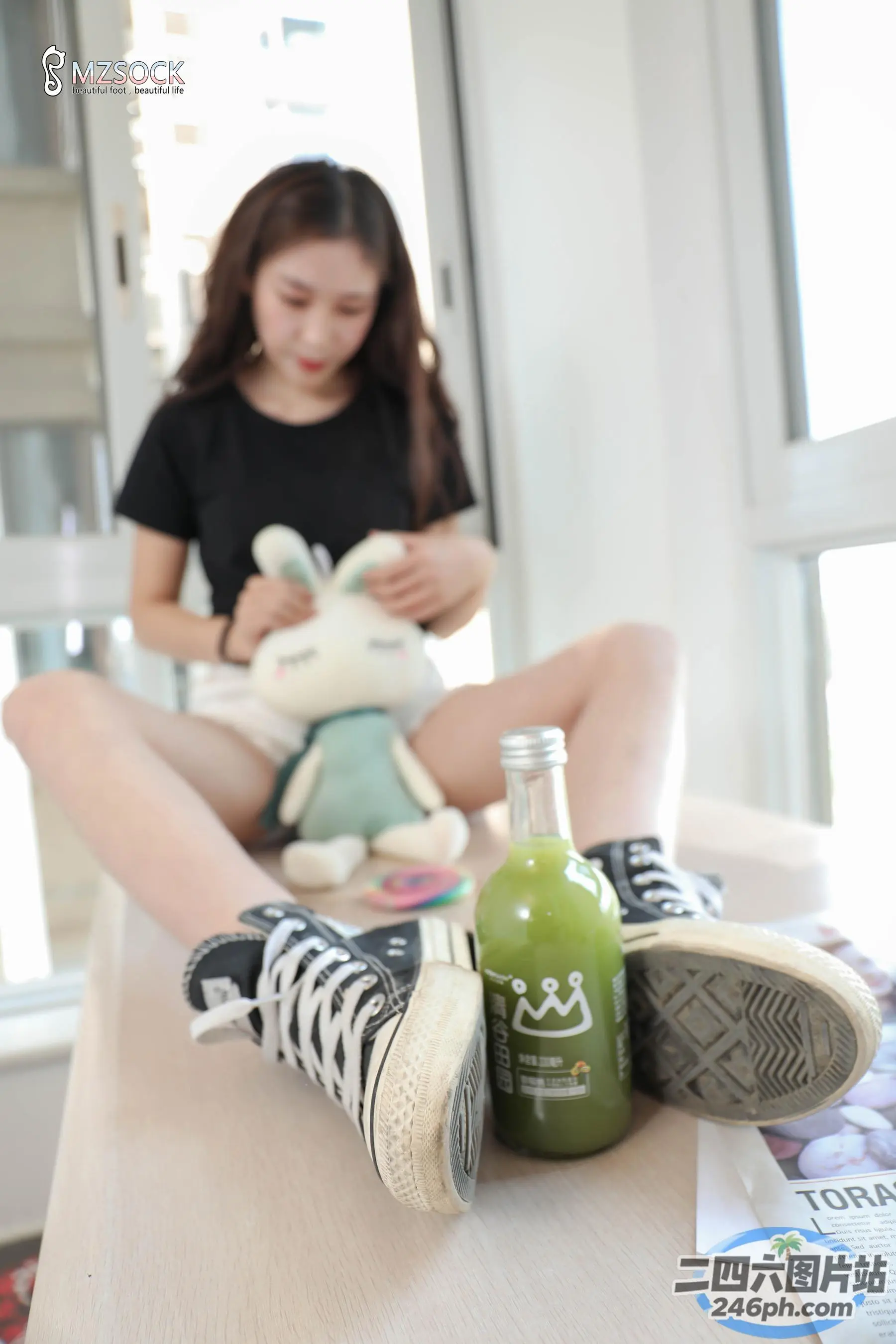 桌上坐着一个女孩，手里拿着一瓶果汁