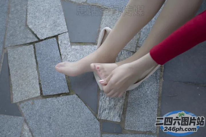 有人坐在石头地板上，脚踩着一双鞋