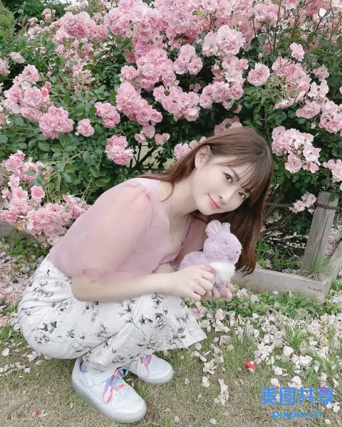 跪在一丛粉红色花朵前的 araffe 女孩