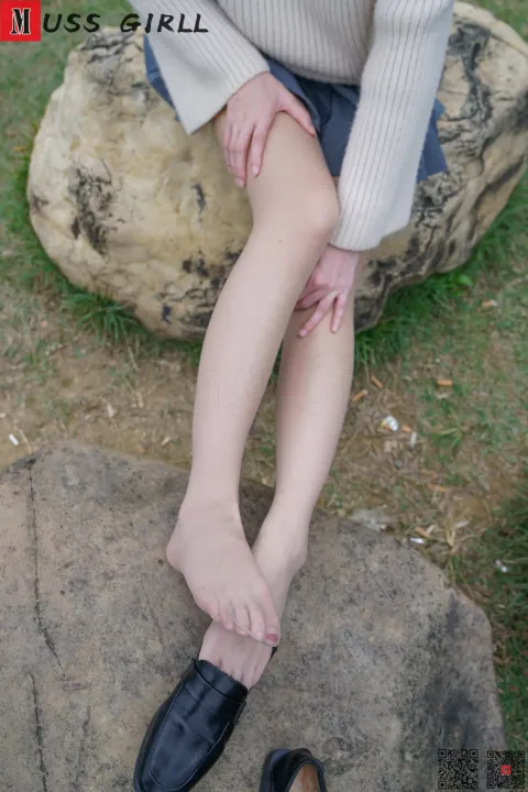 有一个女人坐在一块石头上，脚踩着鞋子
