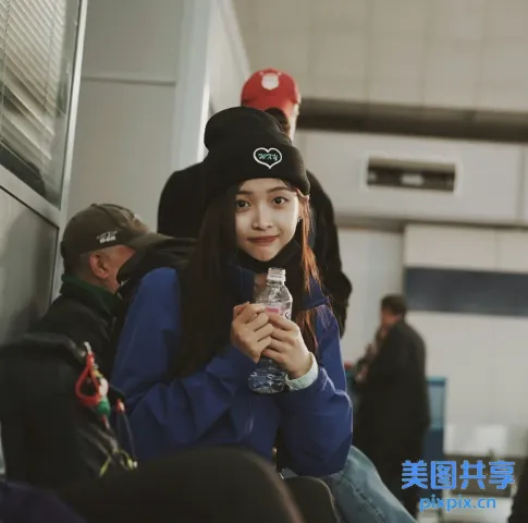 坐在长凳上拿着一瓶水的阿拉夫女孩