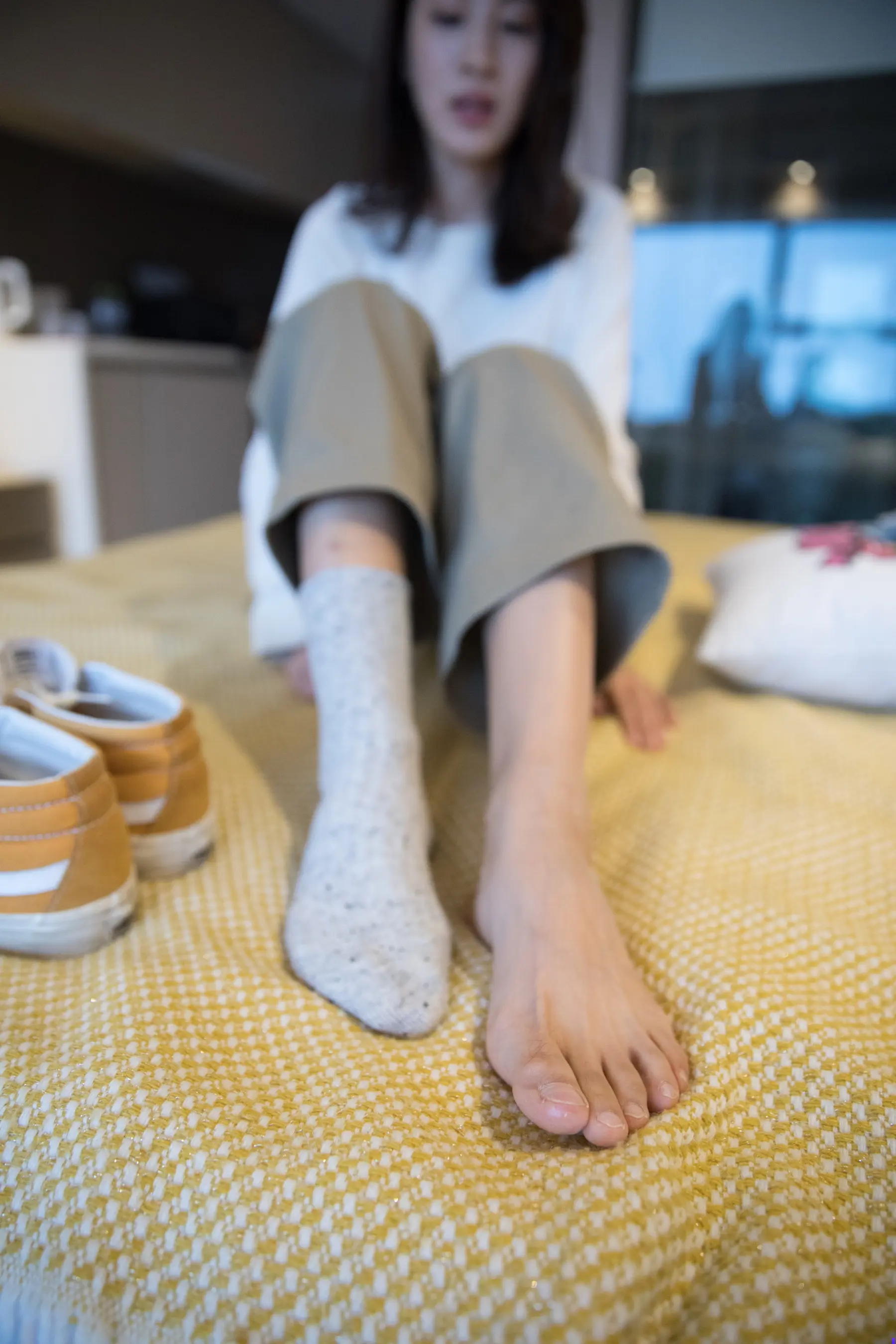 有一个女人坐在床上，双脚抬起